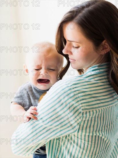 Mother consoling baby boy (6-11 months) indoors