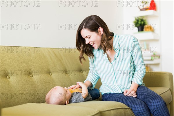 Mother sitting on sofa playing with baby boy (6-11 months)