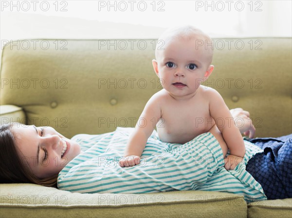 Mother and baby boy (6-11 months) lying on sofa