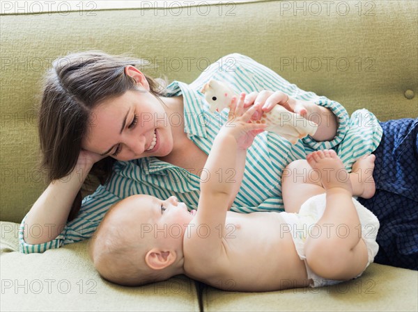 Mother with son (6-11 months) lying on sofa