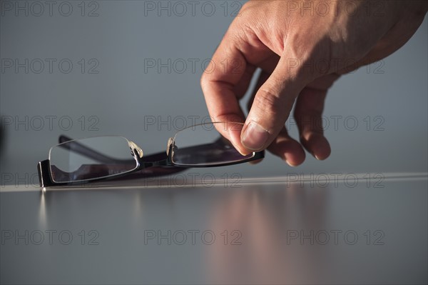 Studio shot of hand reaching for eyeglasses.