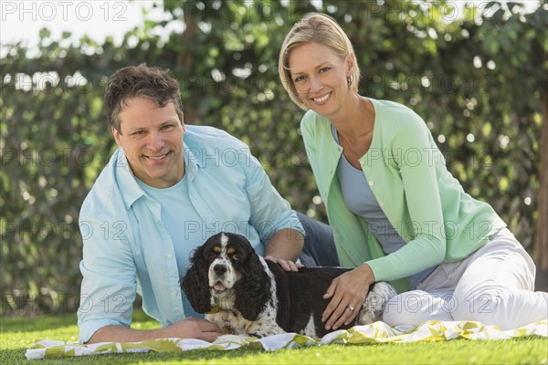 Couple with dog relaxing on grass.