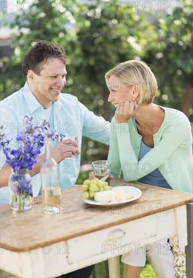 Couple sitting at table outdoors.