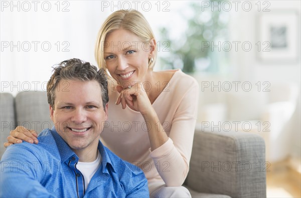 Portrait of couple sitting on sofa.