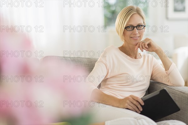 Portrait of woman sitting on sofa holding tablet pc.