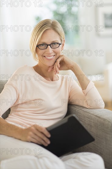 Portrait of woman sitting on sofa holding tablet pc.