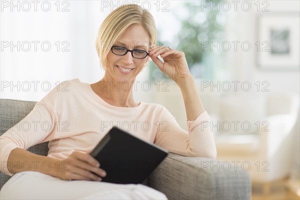 Woman sitting on sofa using tablet pc.