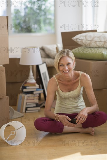 Portrait of woman sitting on floor of new home.