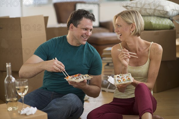 Couple eating sushi in new home.