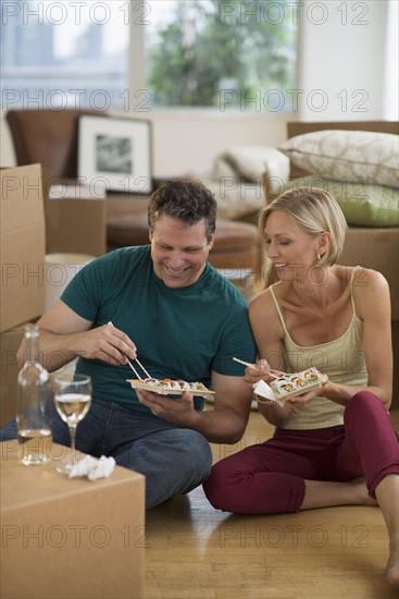 Couple eating sushi in new home.