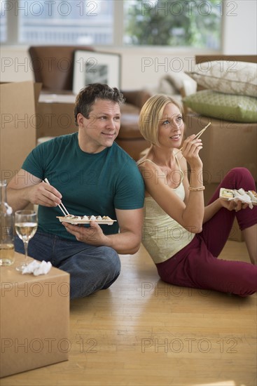 Couple eating sushi in new home.