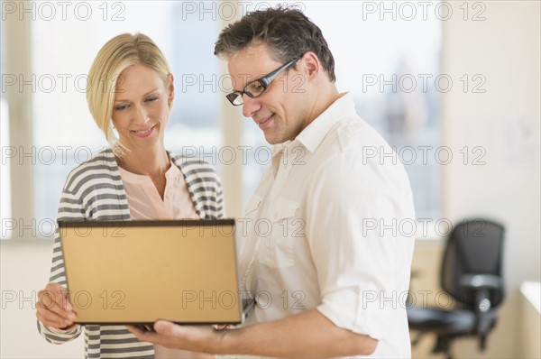 Business man and woman holding laptop.