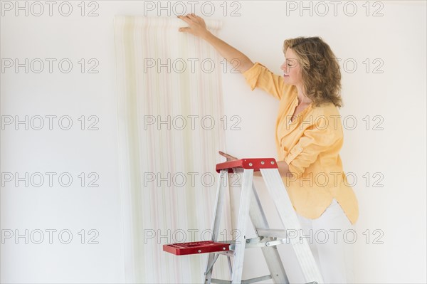 Woman trying out new wallpaper at home.