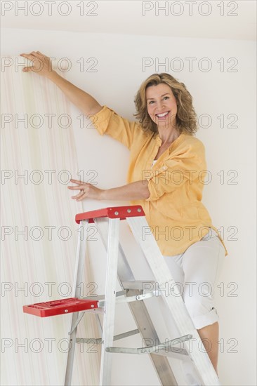 Woman trying out new wallpaper at home.