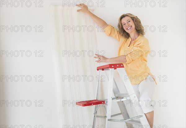 Woman trying out new wallpaper at home.