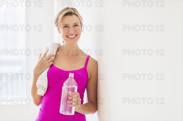 Portrait of woman in sports clothing holding water bottle.