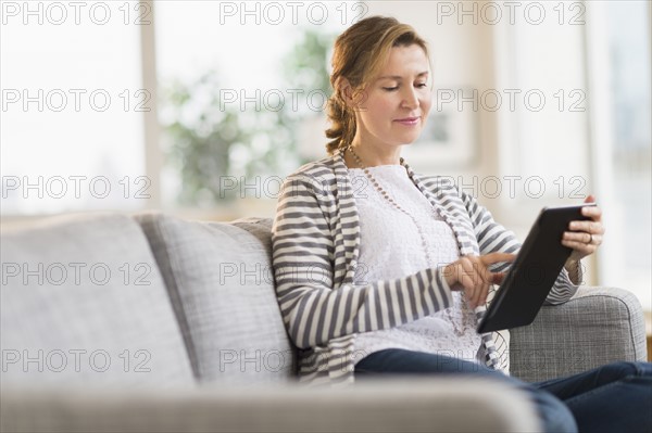 Woman sitting on sofa using tablet pc.