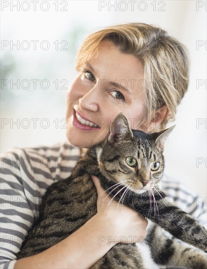 Portrait of woman hugging cat.