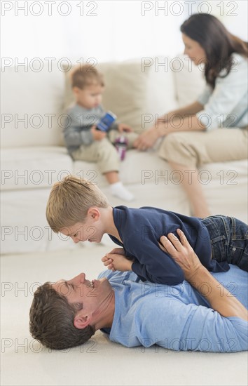 Parents with kids (12-17 months, 6-7) playing at home.