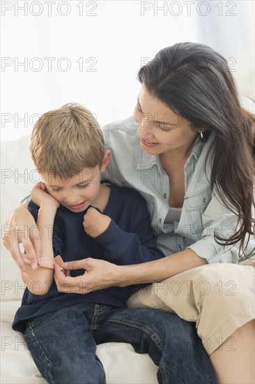 Mother helping son (6-7) put on bandaid.