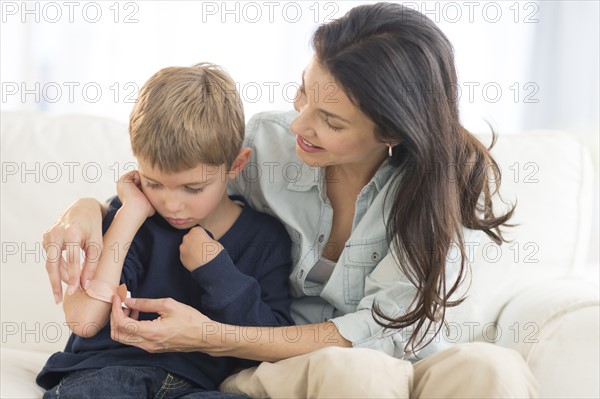 Mother helping son (6-7) put on bandaid.