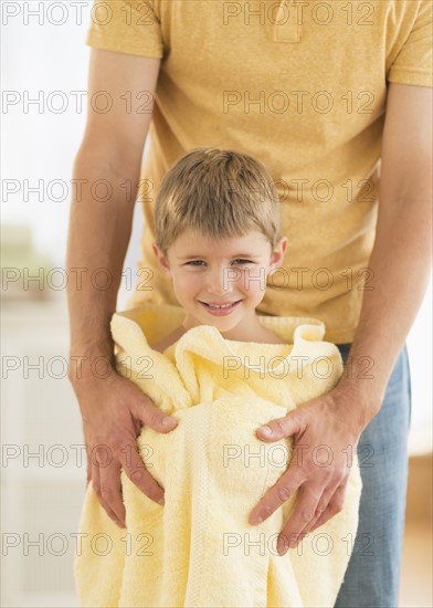 Father with son (6-7) wrapped in towel.