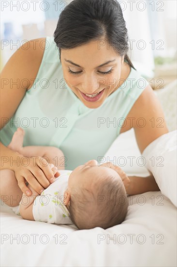 Mother and baby (2-5 months) lying on bed.