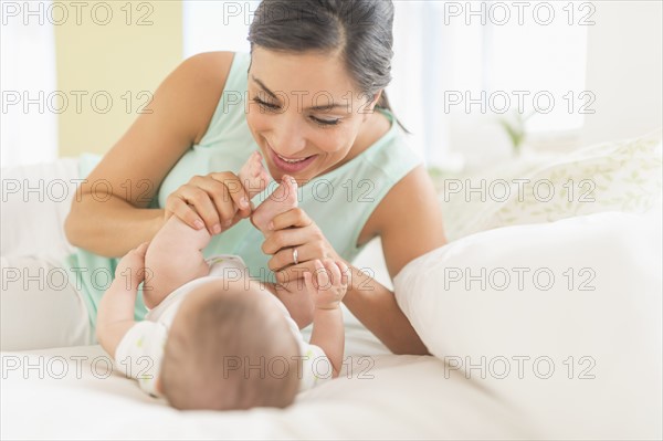 Mother and baby (2-5 months) lying on bed.