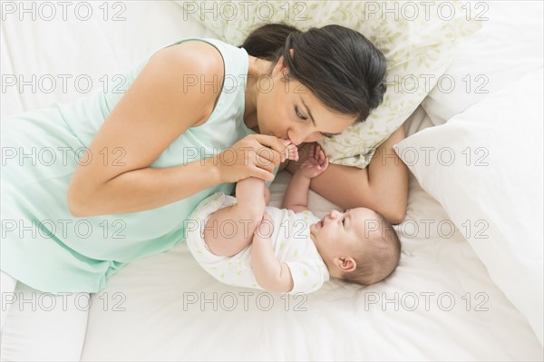 Mother and baby (2-5 months) lying on bed.