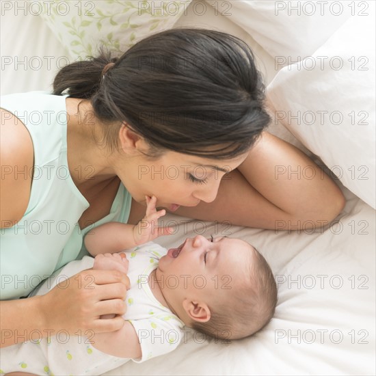 Mother and baby (2-5 months) lying on bed.