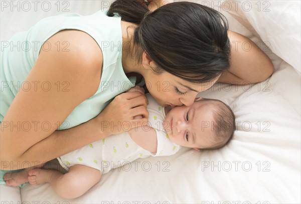 Mother and baby (2-5 months) lying on bed.