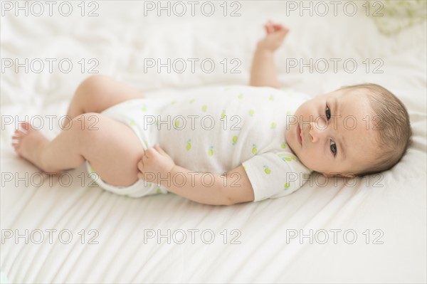Baby boy (2-5 months) lying on bed.