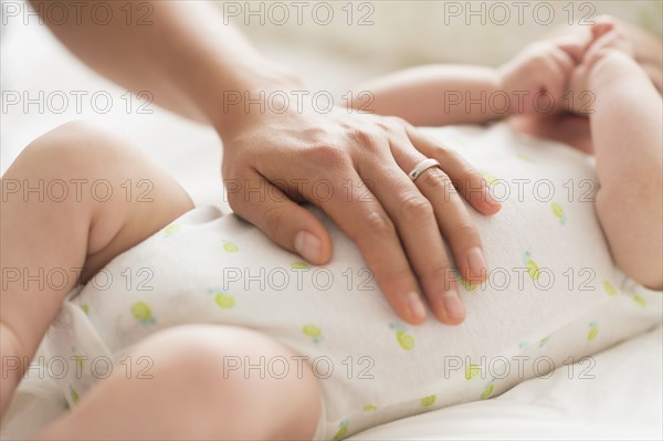 Mother massaging belly of baby boy (2-5 months).