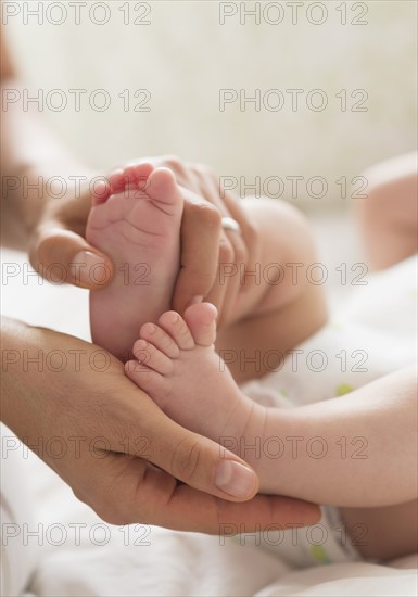 Mother holding feet of baby boy (2-5 months).