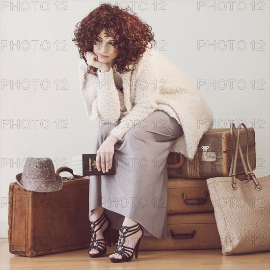 Beautiful brunette woman sitting on suitcases.