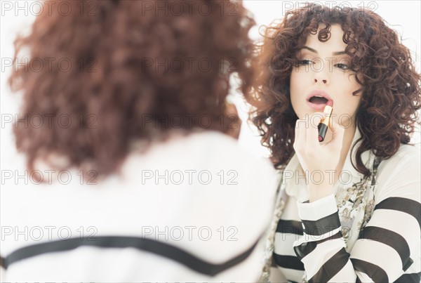 Beautiful brunette woman applying lipstick.