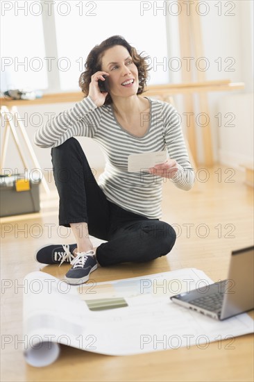 Woman talking on cell phone and using laptop.