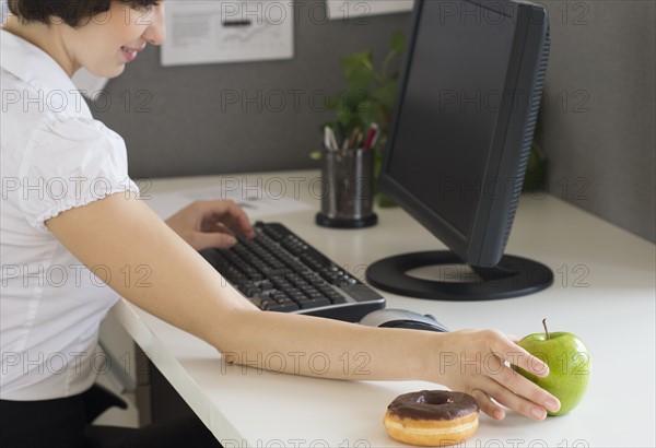 Businesswoman reaching for apple.
Photo : Jamie Grill