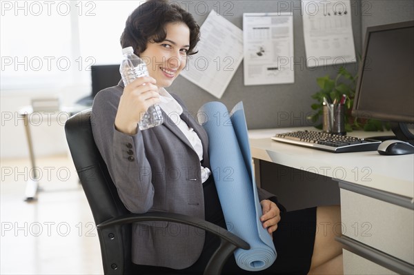 Business woman holding water bottle and yoga mat.
Photo : Jamie Grill