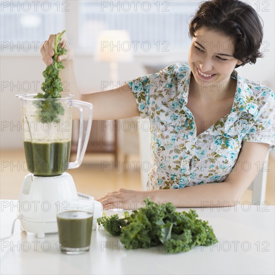 Woman preparing healthy drink with kale.
Photo : Jamie Grill