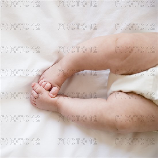 Feet of baby girl (2-5 months) lying on bed.
Photo : Jamie Grill