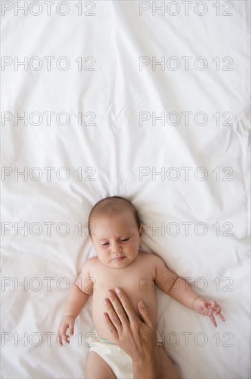 Mother touching belly of baby girl (2-5 months).
Photo : Jamie Grill