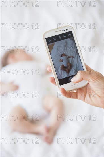 Mother photographing baby girl (2-5 months) sleeping in bed.
Photo : Jamie Grill