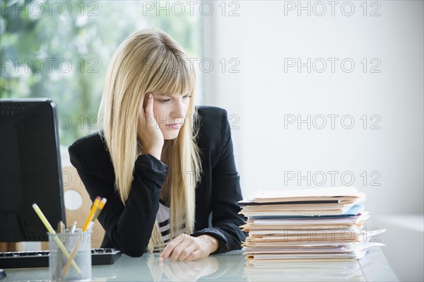 Businesswoman looking at stack of files.
Photo : Jamie Grill