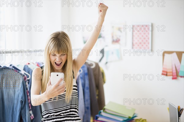 Woman looking at cell phone and cheering.
Photo : Jamie Grill