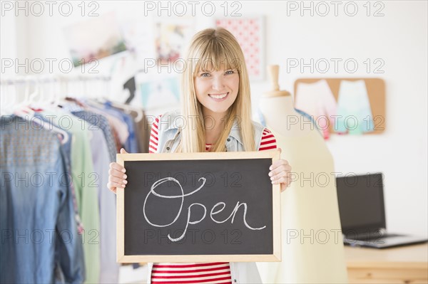 Portrait of female business owner holding open sign.
Photo : Jamie Grill