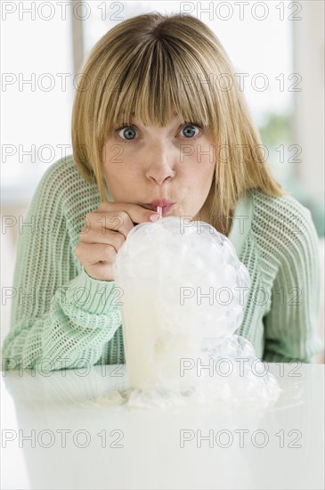 Portrait of woman blowing bubbles in milkshake.
Photo : Jamie Grill