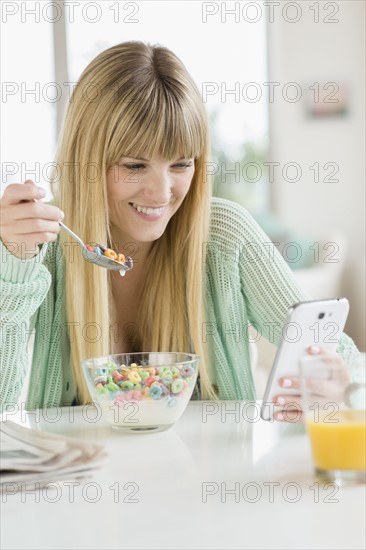 Woman using phone while eating cereal.
Photo : Jamie Grill