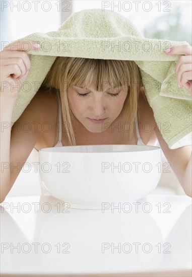 Woman inhaling steam from bowl.
Photo : Jamie Grill