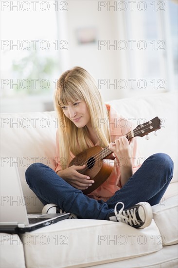 Woman playing ukulele while using laptop.
Photo : Jamie Grill